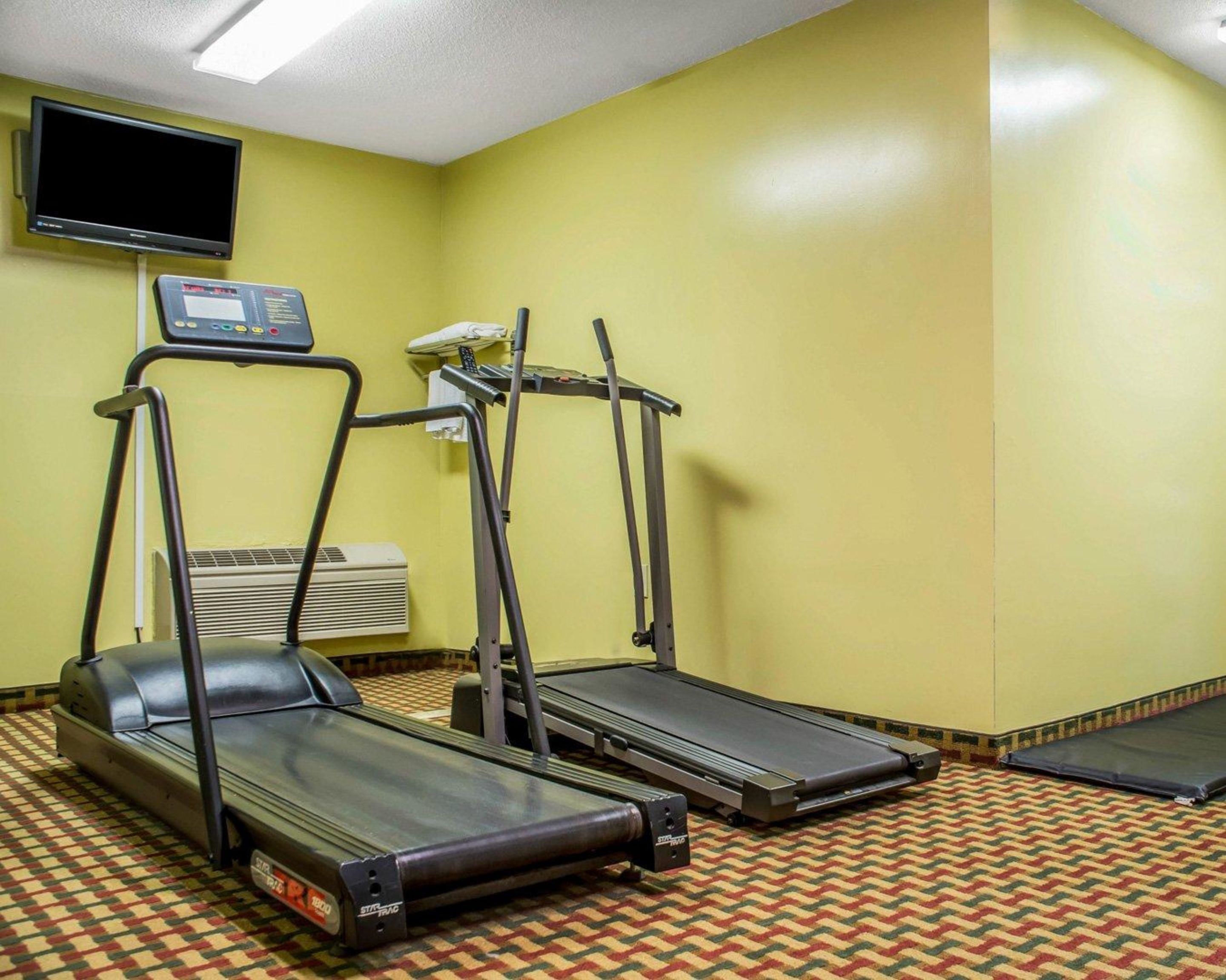 Un gimnasio con cintas de correr, una bicicleta estática y un panel de control.
