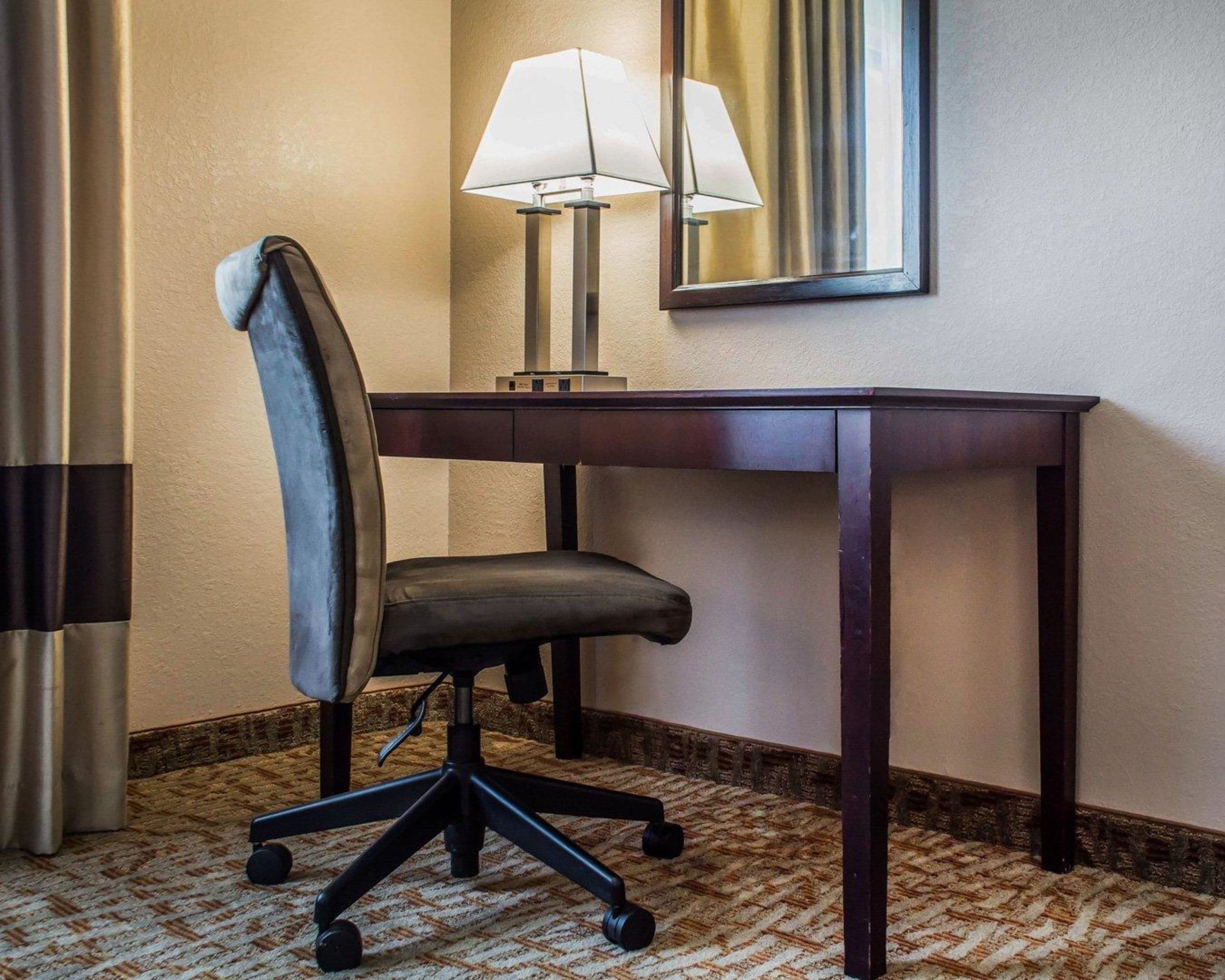 Une chambre d’hôtel équipée d’un bureau, d’une chaise, d’une lampe et d’un miroir.