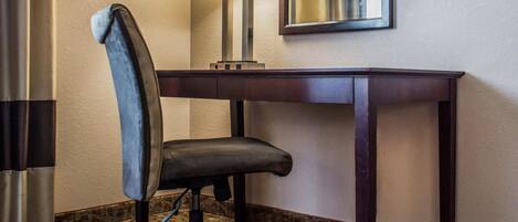 Une chambre d’hôtel équipée d’un bureau, d’une chaise, d’une lampe et d’un miroir.