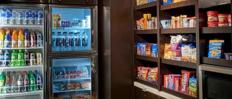 A vending machine with various beverages and snacks, and a shelf stocked with boxed food items.