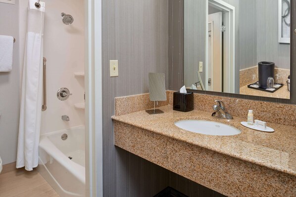 A bathroom with a bathtub, a sink, and a mirror.