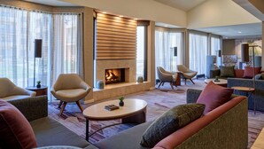 Una sala de estar moderna con chimenea, asientos cómodos y ventanas amplias.