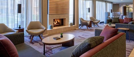 Una sala de estar moderna con chimenea, asientos cómodos y ventanas amplias.