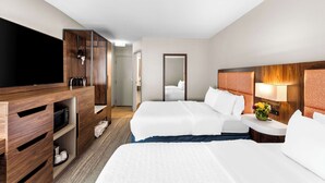 A hotel room with two beds, a TV, a wooden cabinet, and a nightstand with a lamp. - Hampton Inn Knoxville - Airport (Alcoa)