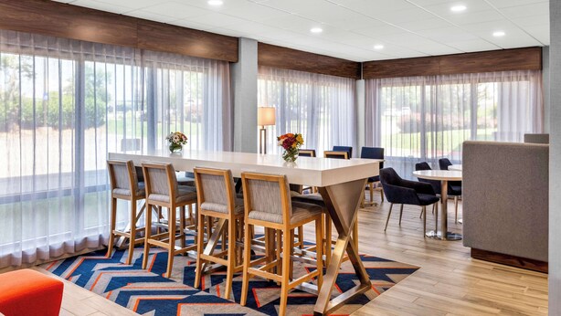 A hotel dining area with a long table, chairs, and a patterned rug. - Hampton Inn Knoxville - Airport (Alcoa)
