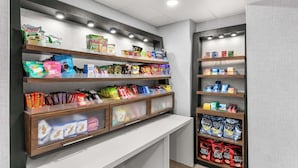 A snack display with various packaged snacks and a white counter. - Hampton Inn Knoxville - Airport (Alcoa)