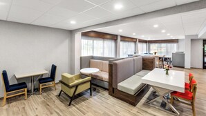 A modern hotel lobby with a seating area, a dining table, and a bar. - Hampton Inn Knoxville - Airport (Alcoa)