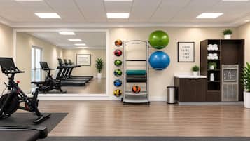 Un gimnasio con equipo de ejercicio, un soporte de pared para balones y decoración motivacional.