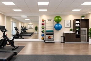 A gym with exercise equipment, a wall-mounted ball rack, and motivational decor.