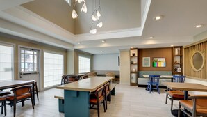 A spacious dining area with multiple tables and chairs, a central island, and a seating area with a bench and chairs. - Sonesta ES Suites San Jose Airport (San Jose)