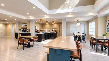 A spacious kitchen with modern appliances, a dining area with wooden tables and chairs, and a large island with bar stools.