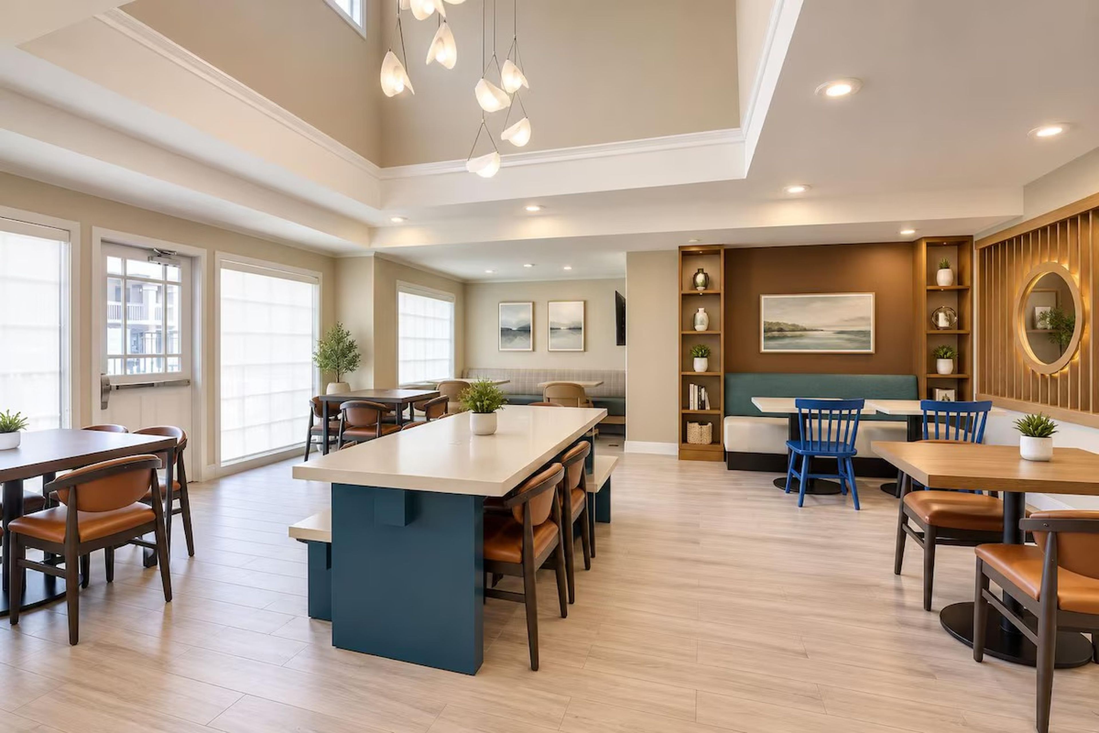 A spacious dining area with a central island, multiple seating arrangements, and a view of the outdoors.