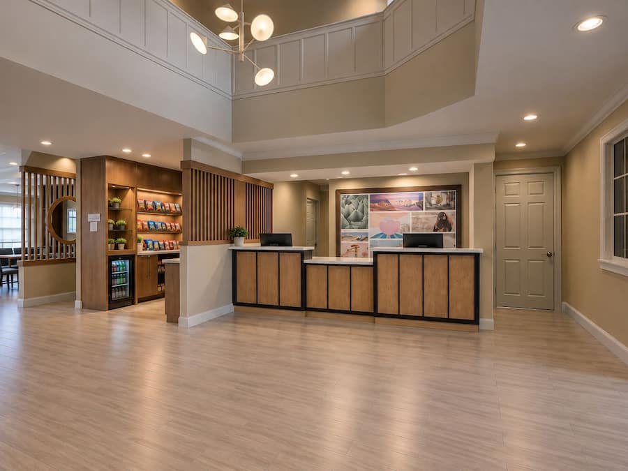 A reception area with a wooden reception desk, a seating area with chairs, and a wall with a collage of images.