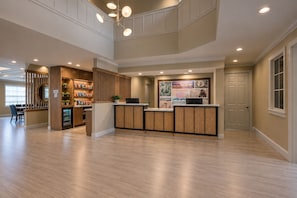 Un área de recepción con mostrador de madera, un espacio de estar con sillas y una pared con un collage de imágenes.