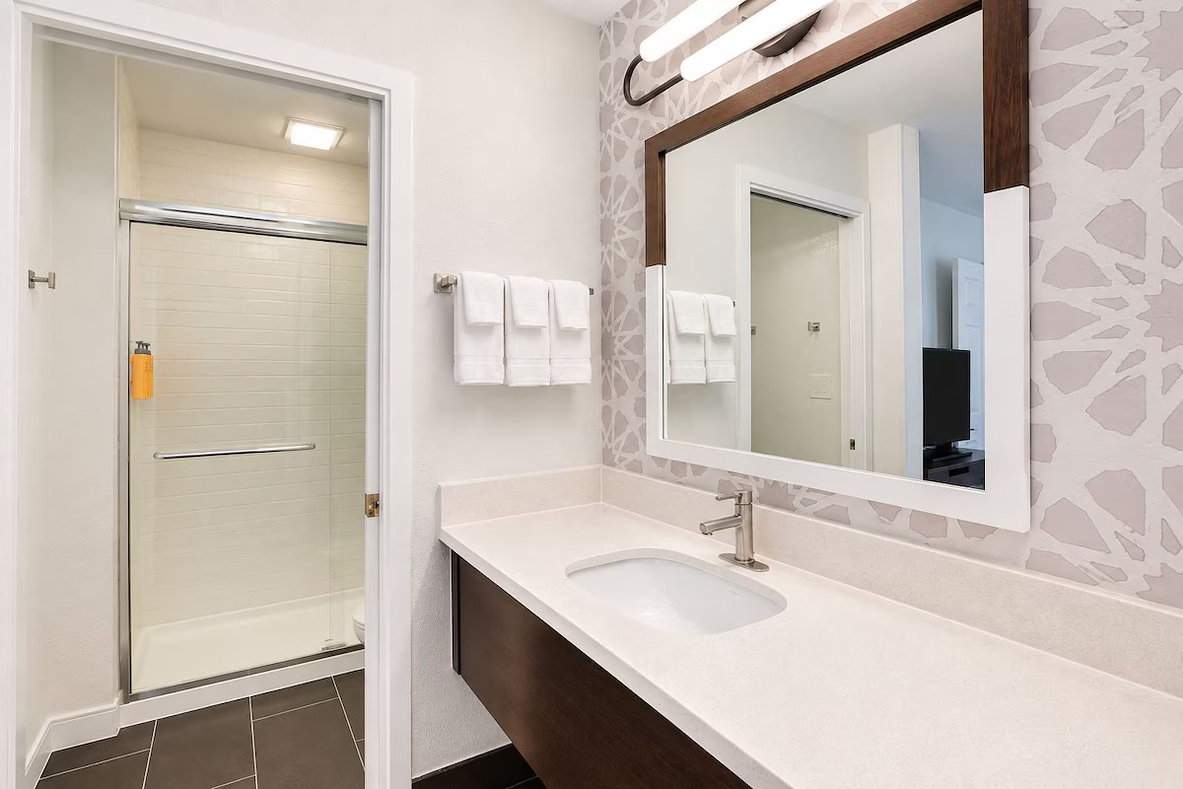 A bathroom with a shower, a sink, and a mirror.