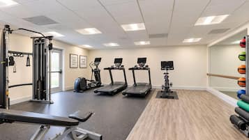 Un gimnasio con cintas de correr, máquinas de pesas y pelotas de ejercicio.