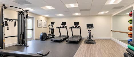 A gym with treadmills, a weight machine, and exercise balls.