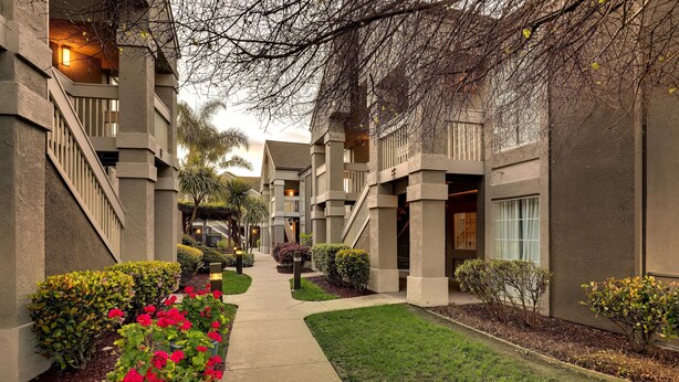 A corridor with a central pathway flanked by buildings with balconies and windows. - Sonesta ES Suites San Jose Airport (San Jose)