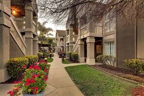 Stroll through the beautifully manicured grounds, flanked by lush hedges and shrubs, to the secure gated entrance.