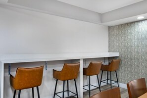 Eine Bar mit einer weißen Arbeitsplatte und vier braunen Barhocker.