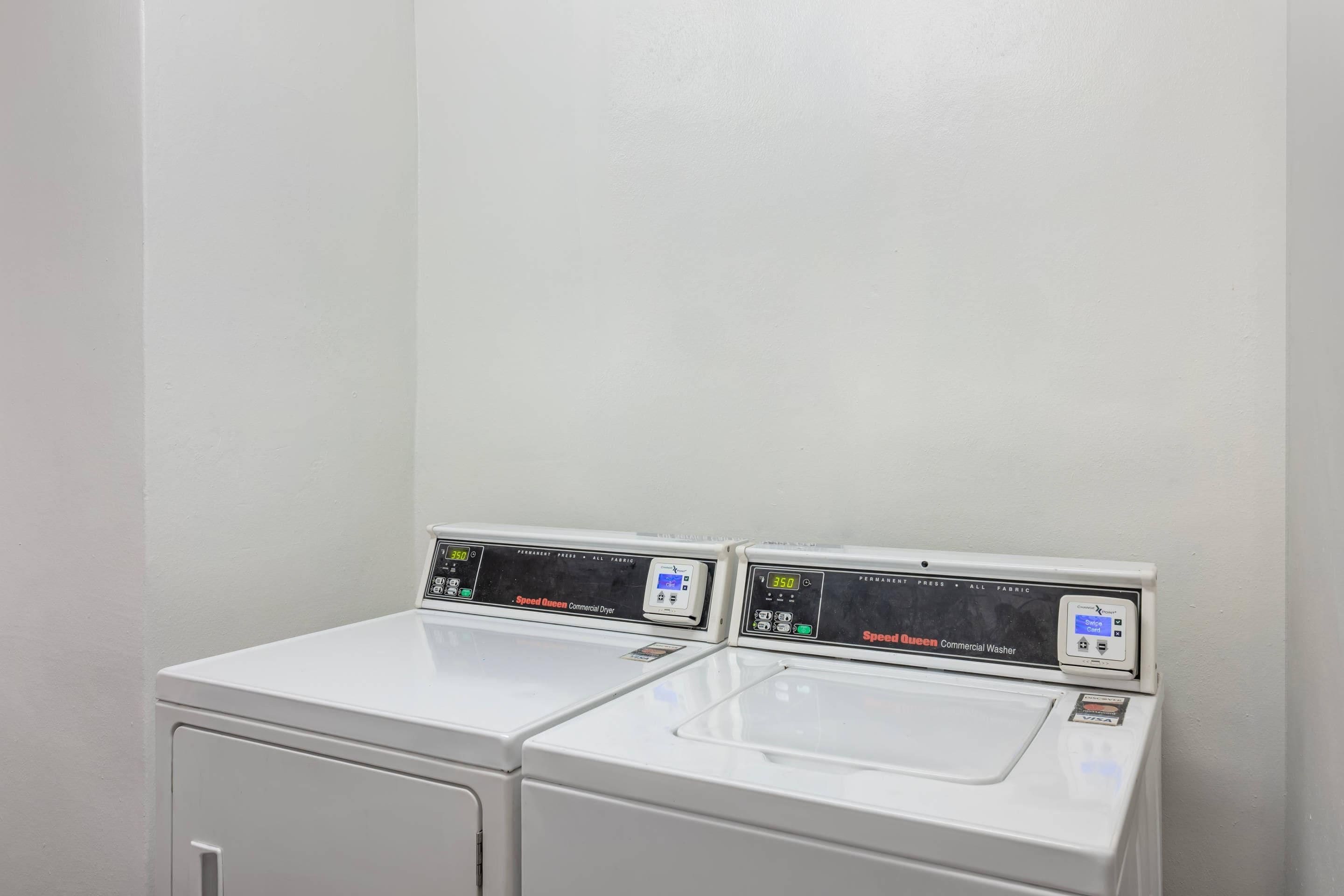 A white commercial washer and dryer unit with digital displays, a card reader, and a visible payment option.