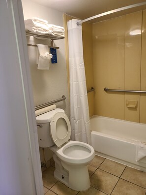 Une salle de bain comprenant des toilettes, une douche avec un rideau blanc et une baignoire.