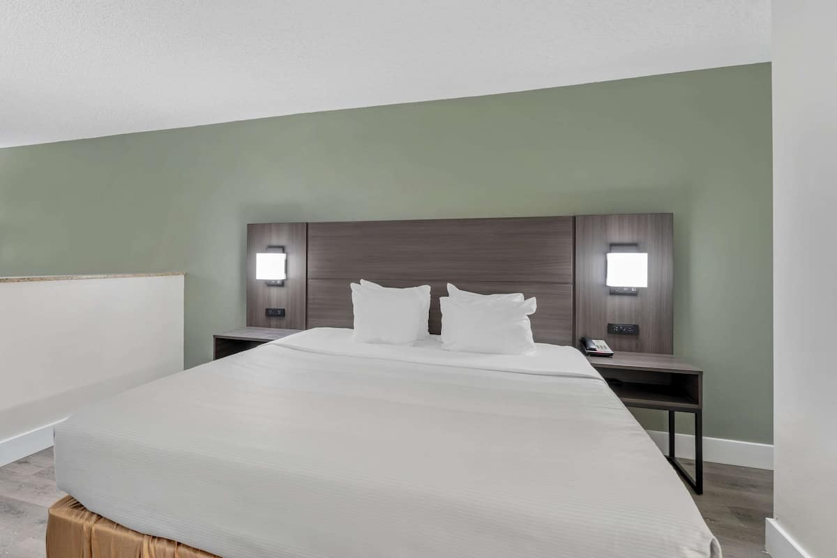 A hotel room with a large bed, two bedside tables, and wall-mounted lights.