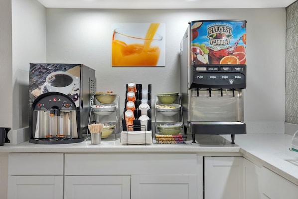 A kitchenette with a coffee machine, a juice dispenser, and various kitchenware. - Quality Inn & Suites Orlando East - UCF Area (Orlando)