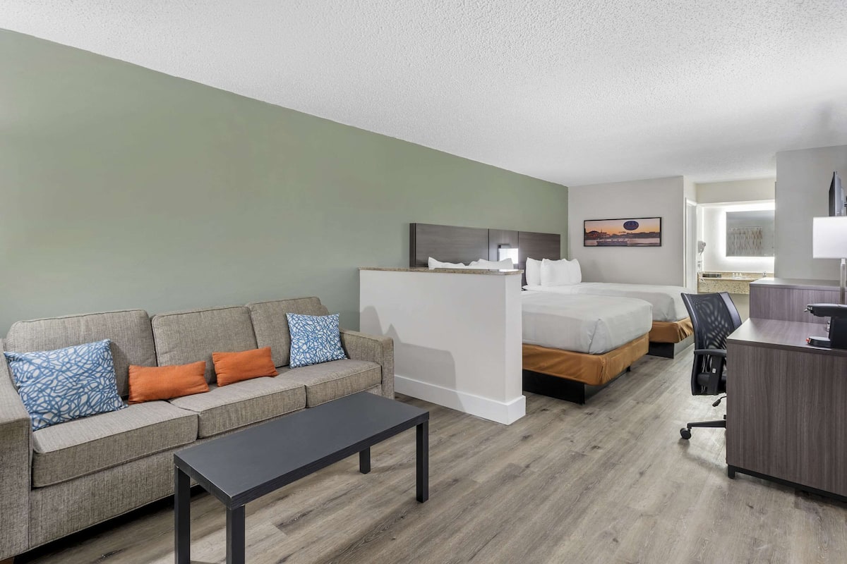 A hotel room with a sofa, a bed, a desk, and a chair.