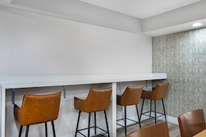 A bar area with a white countertop and four brown chairs. - Quality Inn & Suites Orlando East - UCF Area (Orlando)