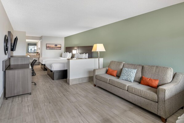 A hotel room with a bed, a desk, a sofa, and a lamp.