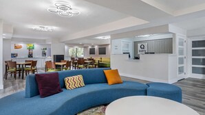 A modern hotel lobby with a blue sofa, a round table, and a reception desk.