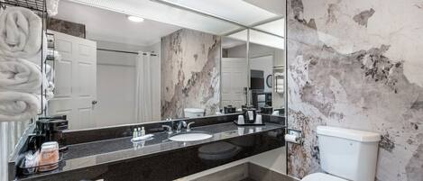 A modern bathroom with a black granite countertop, white toilet, and marble walls.