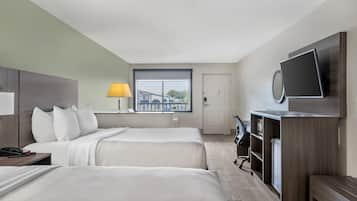 Habitación de hotel con dos camas, un escritorio, una silla, un televisor y una ventana con vista a edificios.