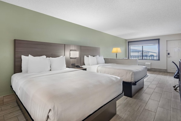 A hotel room with two beds, a desk, a chair, and a window with a view. - Quality Inn & Suites Orlando East - UCF Area (Orlando)