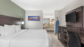 Habitación de hotel con una cama, un escritorio, un televisor y un baño a la vista.