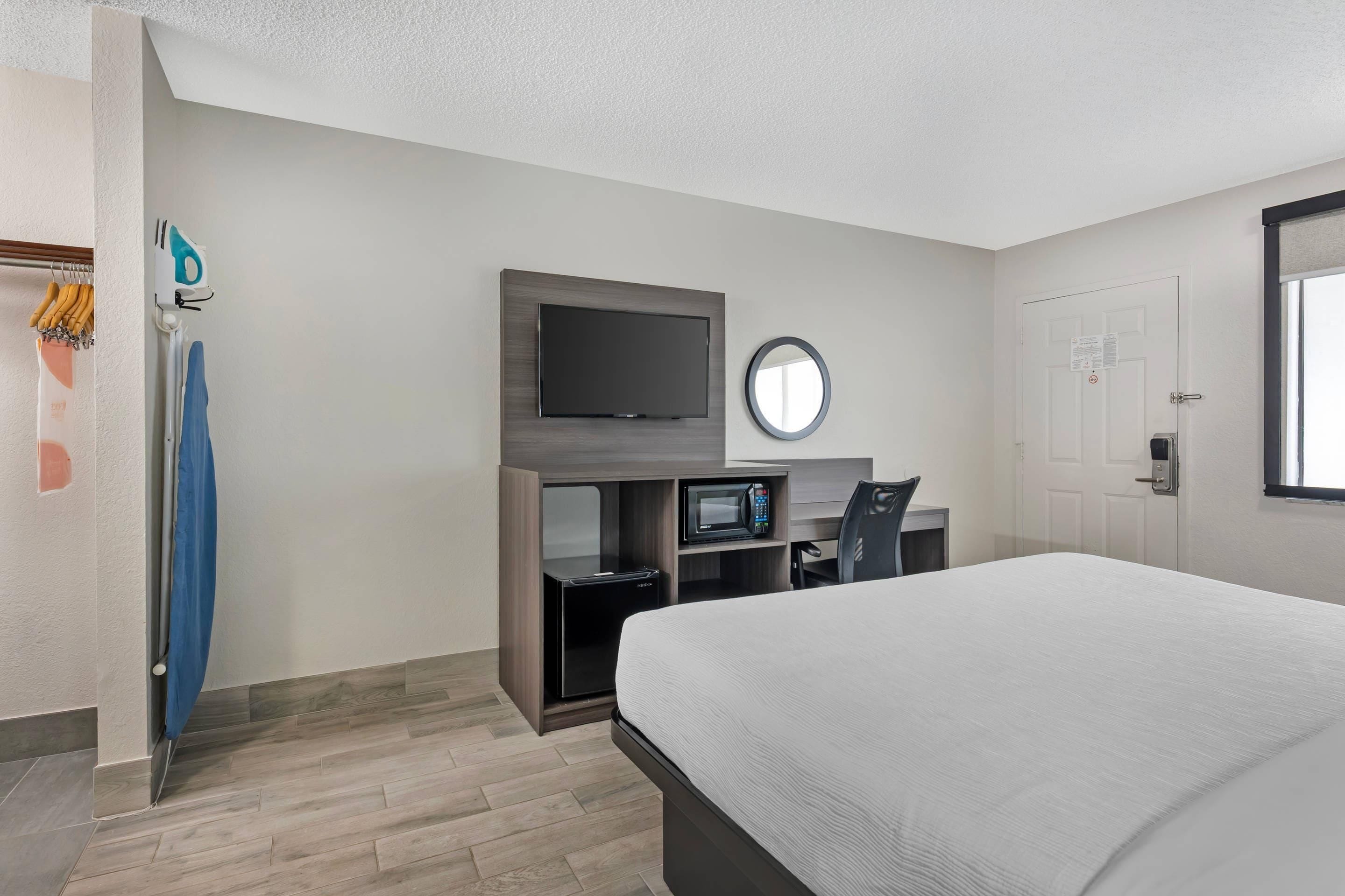 A hotel room with a bed, a TV, a microwave, and a desk with a chair.