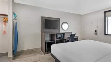 A hotel room with a bed, a TV, a microwave, and a desk with a chair.