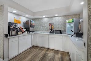 A modern kitchen with white cabinets, a coffee machine, a microwave, and a refrigerator.