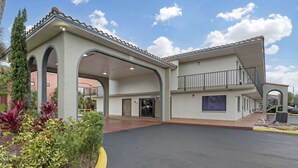 A building with a covered entrance, multiple arches, and a balcony.
