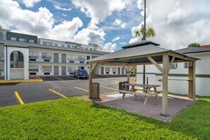 A parking area with a covered picnic table and a trash bin. - Quality Inn & Suites Orlando East - UCF Area (Orlando)