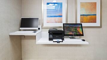 Un espace de travail comprenant un ordinateur de bureau, un écran et une imprimante, le tout posé sur un bureau blanc devant un mur texturé.