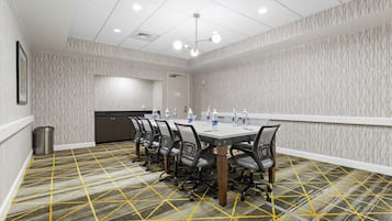 Une salle de conférence avec une longue table, des chaises et un tapis à motifs.