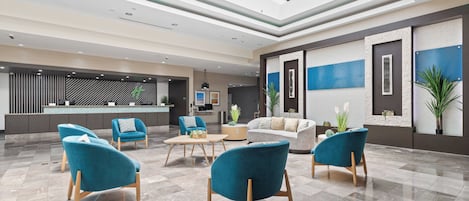 Um hall espaçoso com teto alto, balcão de recepção e várias áreas de estar com cadeiras modernas.