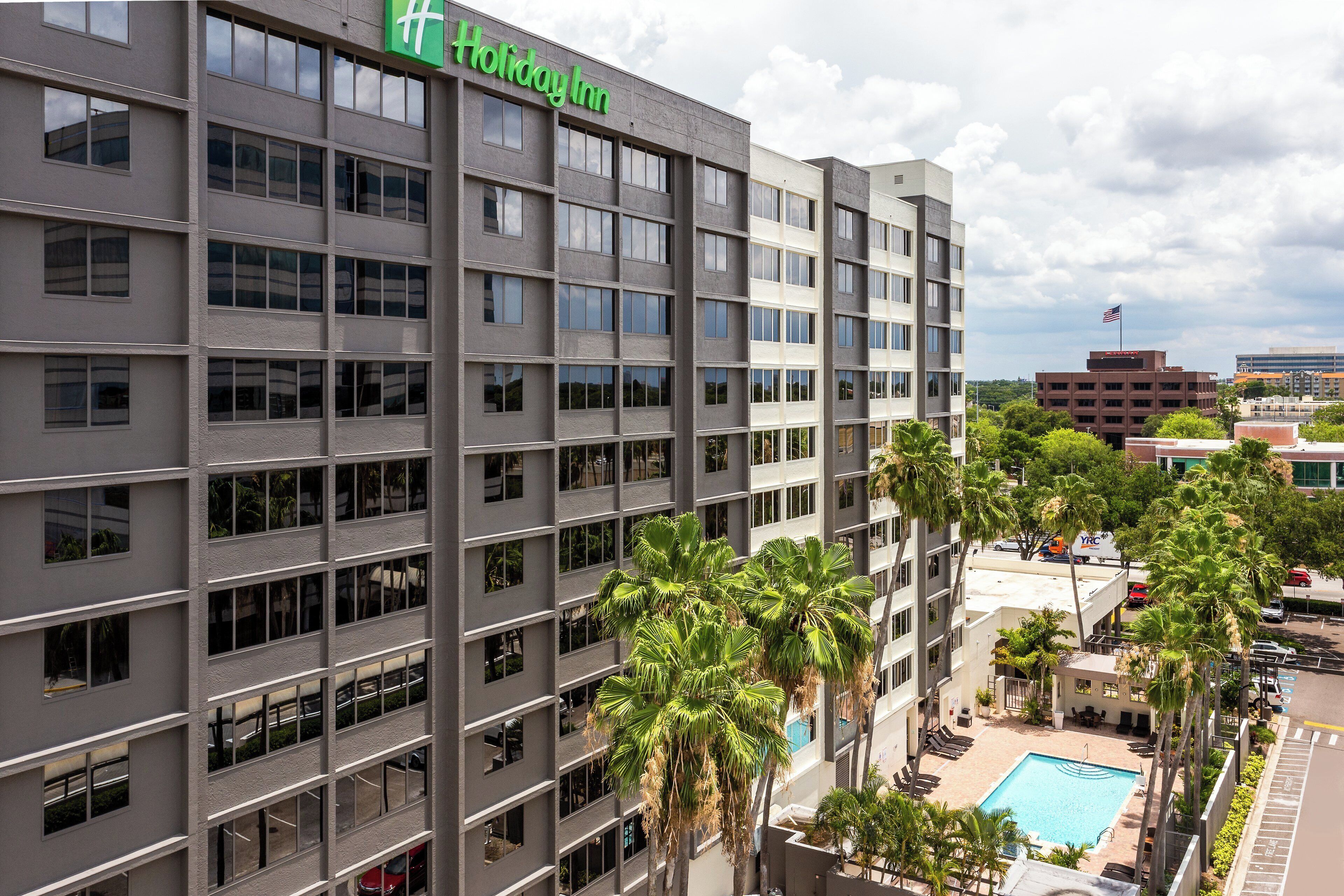 A Holiday Inn hotel with multiple floors, a swimming pool, and palm trees.