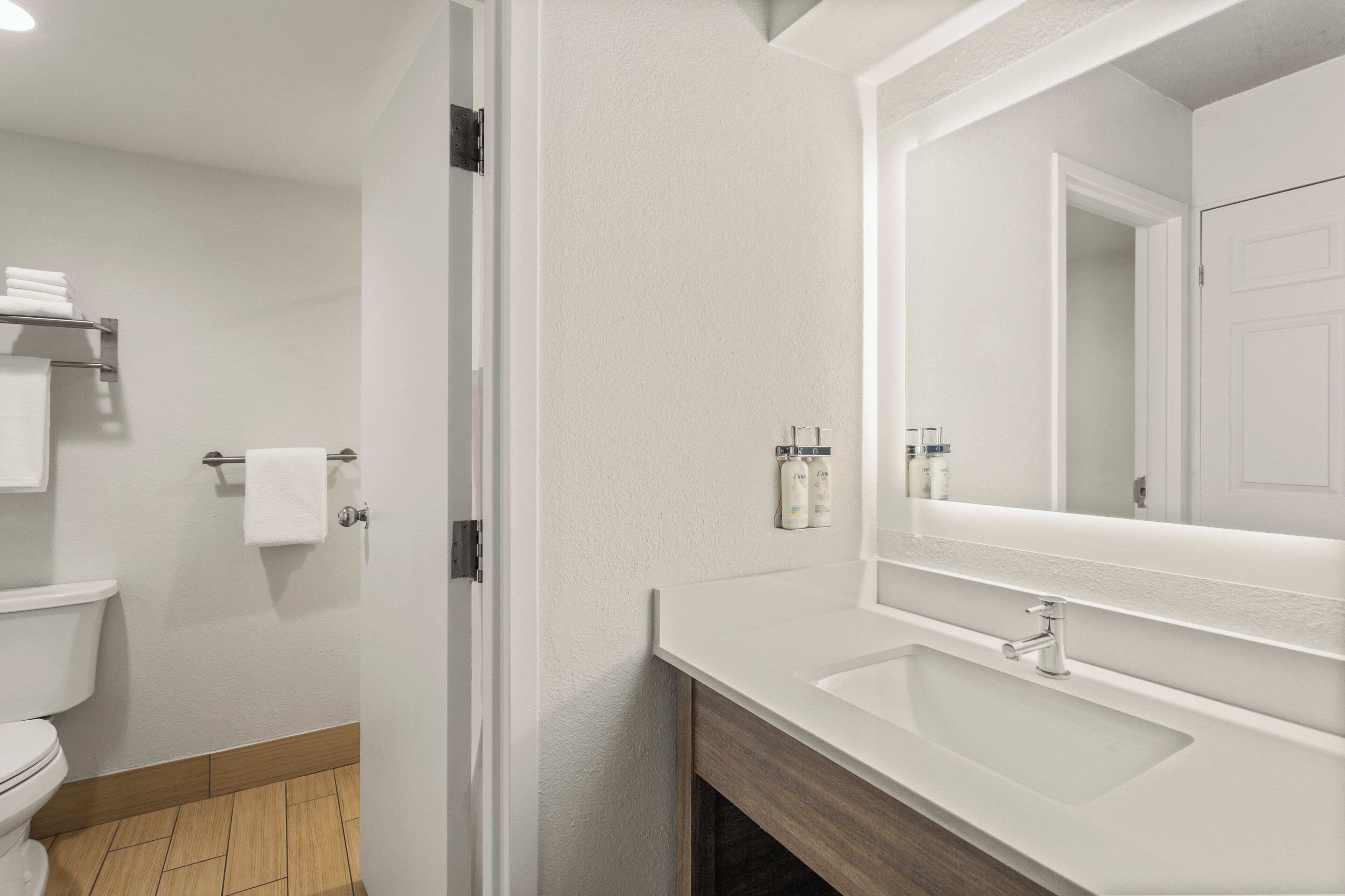 Un baño con lavamanos, espejo y retrete.