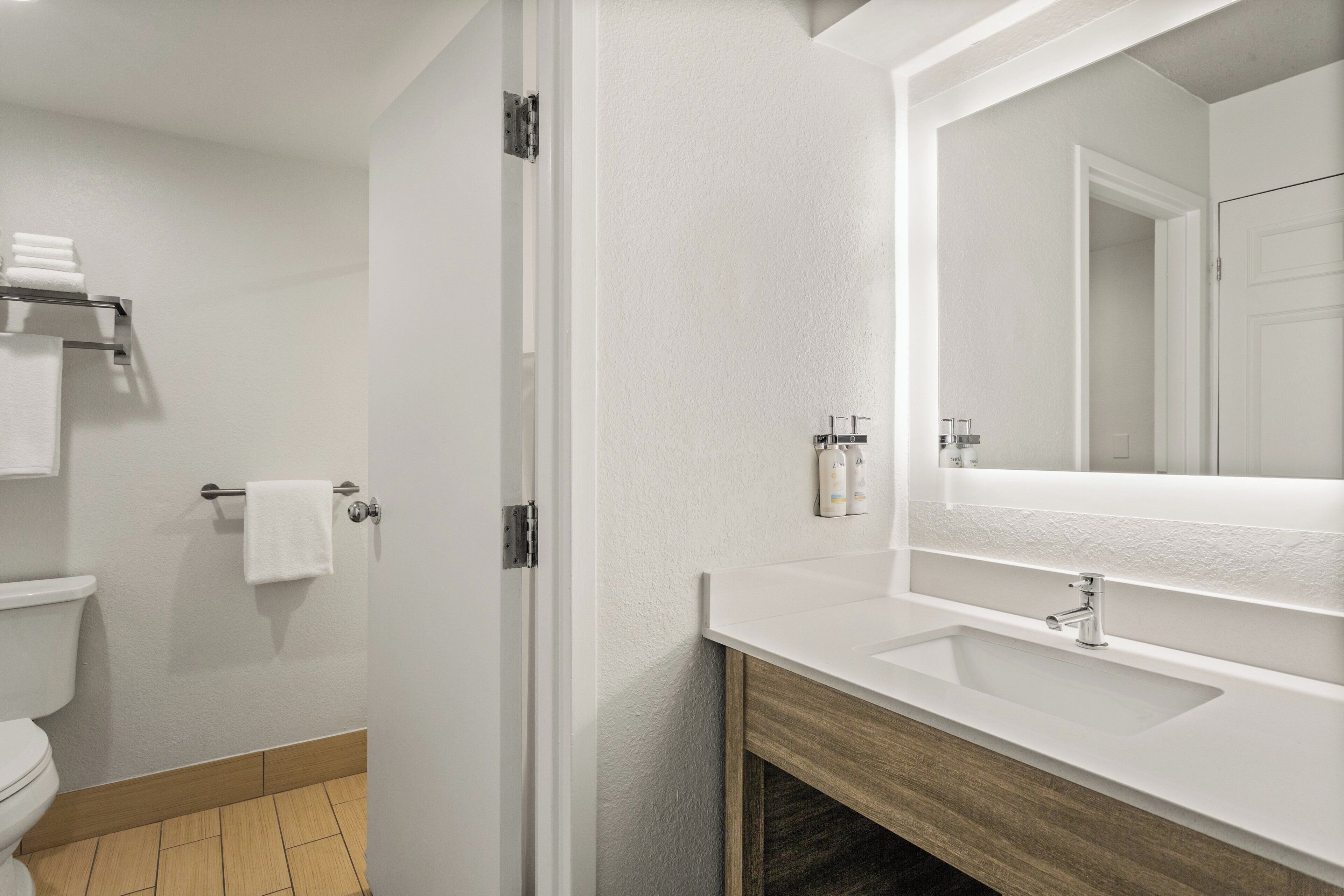 Ein modernes Badezimmer mit einem weißen Waschbecken, einem großen Spiegel und einer Toilette.