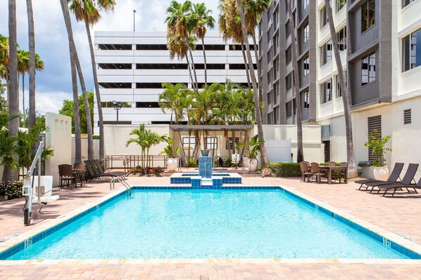 Una piscina al aire libre, sombrillas, sillones reclinables de piscina