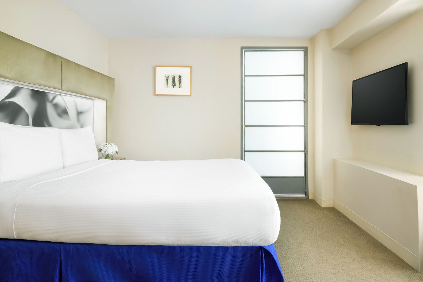 Ein Hotelzimmer mit einem großen Bett, einem flachbildfernseher an der Wand und einem Fenster mit Blick nach draußen.