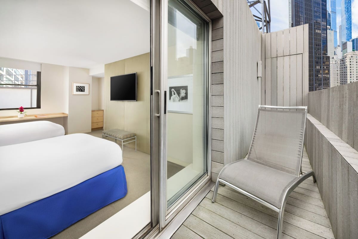 A hotel room with a bed, a desk, a chair, and a large window.